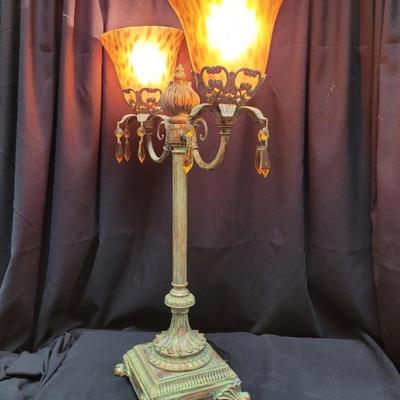 Sale Photo Thumbnail #224: Two-arm candelabra in patinated brass with mottled glass shades.
21 inches tall, 15 inches wide. 
good condition. 
A few of the crystal drops are missing.