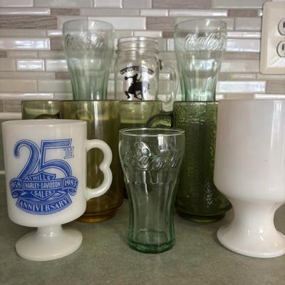 LOT 90: Glass Collection with Avocado Green Glass Mugs, Amber Glass Mug, Milk Glass, 25th Harley Davidson Mug, Coca-Cola Glasses, Cowtown...