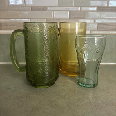 LOT 90: Glass Collection with Avocado Green Glass Mugs, Amber Glass Mug, Milk Glass, 25th Harley Davidson Mug, Coca-Cola Glasses, Cowtown...