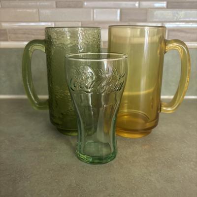 LOT 90: Glass Collection with Avocado Green Glass Mugs, Amber Glass Mug, Milk Glass, 25th Harley Davidson Mug, Coca-Cola Glasses, Cowtown...