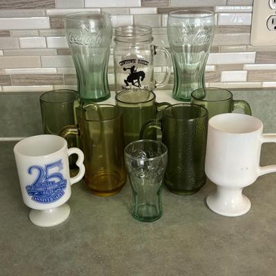 LOT 90: Glass Collection with Avocado Green Glass Mugs, Amber Glass Mug, Milk Glass, 25th Harley Davidson Mug, Coca-Cola Glasses, Cowtown...