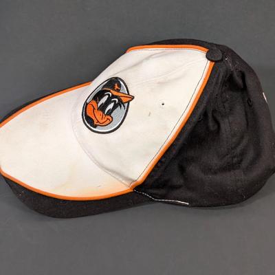 LOT 228: Baltimore Oriole Gear, Button Down Shortsleeve Shirt, Pullover, Sweatshirt, 2 Straw Hats, One Signed & 3 Baseball Caps. No...