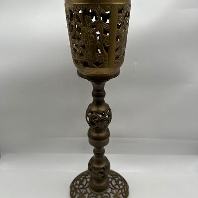 Sale Photo Thumbnail #426: Vintage Chinese brass incense burner stand. This intricately cast and pierced piece features four panels of raised figural scenes, likely depicting scholars or deities in a lush landscape, complete with traditional robes and symbolic foliage. The stem is 