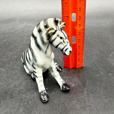 Sale Photo Thumbnail #328: Vintage Sitting Zebra Porcelain Bone China Figurine - Black & White Brown. High gloss finish on this cute zebra figurine. He is white with black stripes, gray hooves and brown around mane, neck, ears and face. Measures 3.25” tall and 4” long. This fig