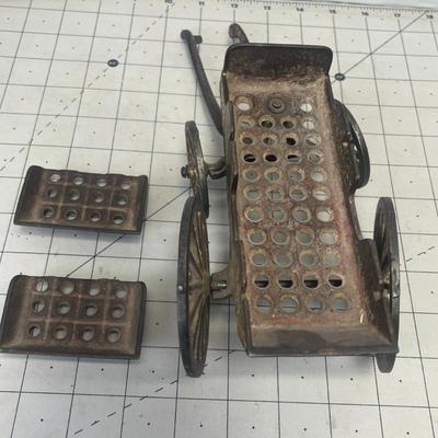 Sale Photo Thumbnail #341: This vintage cast iron toy wagon features a rustic, weathered finish and detailed craftsmanship, including two perforated seats and authentic spoked wheels.