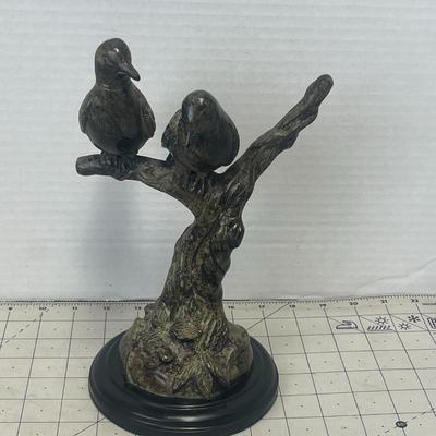 Sale Photo Thumbnail #345: Charming decorative sculpture featuring two birds perched on a textured tree branch with a leafy base, finished in a bronze patina. Cast metal.