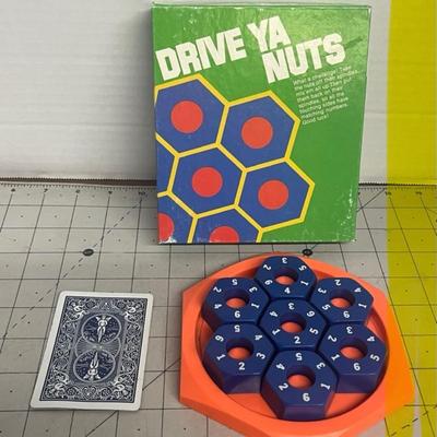 Sale Photo Thumbnail #1399: Put your brain to the test with this vintage Drive Ya Nuts puzzle game, a clever number-matching challenge featuring hexagonal "nuts" and a bold orange tray.
