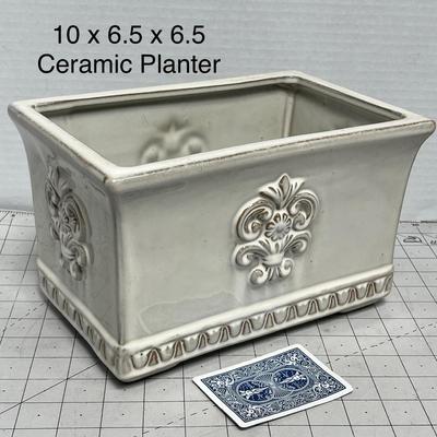 Sale Photo Thumbnail #1591: Elegant 10x6.5x6.5 inch ceramic planter with ornate floral design, perfect for indoor plants or decor.
