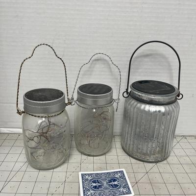 Sale Photo Thumbnail #1607: Set of three rustic solar-powered lanterns with wire handles and internal LED fairy lights, perfect for garden, patio, or indoor ambiance. Larger one may need new solar battery
