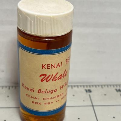 Sale Photo Thumbnail #1687: Small collectible bottle labeled “Kenai Beluga Whale Oil” from Alaska’s Chamber of Commerce, a unique historical memento from whale hunt commemorations.