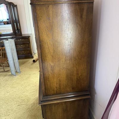 Sale Photo Thumbnail #41: This freestanding wardrobe is a vintage reproduction crafted from dark wood, featuring a classic brown finish. It includes two doors and two drawers, with brass-finished handles, and is designed for bedroom use. The wardrobe requires no assembly or additi