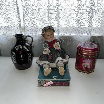 MUSICAL LITTLE BROWN JUG, DOLL AND METAL TIN