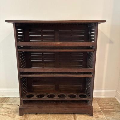 Sale Photo Thumbnail #3: Compact wooden bar cabinet with slatted sides and back, three open shelves, and a bottom rack with slots for storing up to 6 bottles. 

Dimensions: 43.5” tall x 39.5” wide x 16.5” deep
