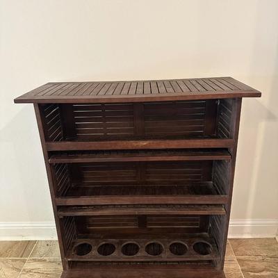 Sale Photo Thumbnail #8: Compact wooden bar cabinet with slatted sides and back, three open shelves, and a bottom rack with slots for storing up to 6 bottles. 

Dimensions: 43.5” tall x 39.5” wide x 16.5” deep