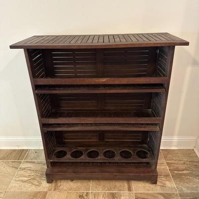Sale Photo Thumbnail #9: Compact wooden bar cabinet with slatted sides and back, three open shelves, and a bottom rack with slots for storing up to 6 bottles. 

Dimensions: 43.5” tall x 39.5” wide x 16.5” deep