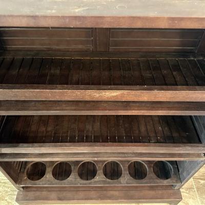 Sale Photo Thumbnail #11: Compact wooden bar cabinet with slatted sides and back, three open shelves, and a bottom rack with slots for storing up to 6 bottles. 

Dimensions: 43.5” tall x 39.5” wide x 16.5” deep