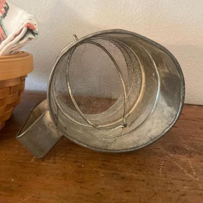 Small basket with dish towels and vintage sifter