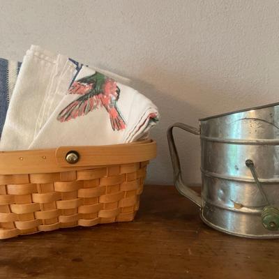 Small basket with dish towels and vintage sifter