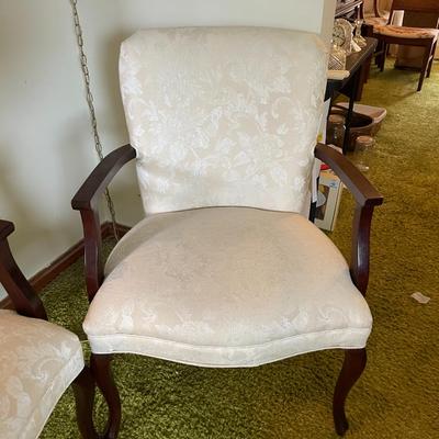 Sale Photo Thumbnail #3: Upholstered armchairs featuring cream fabric with a subtle damask pattern. Chairs have carved wood frames with curved arms and cabriole legs, showcasing classic design elements. Frames are in a polished wood finish. Overall condition appears to be good.