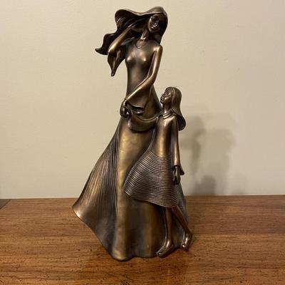 Sale Photo Thumbnail #71: Bronze-colored resin sculpture depicting a woman and a child in a flowing, textured design. Marked with a gold sticker from Austin Productions at the base. The sculpture features detailed attention to the draping of the clothing and hair, evoking movement