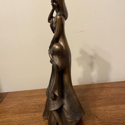 Sale Photo Thumbnail #77: Bronze-colored resin sculpture depicting a woman and a child in a flowing, textured design. Marked with a gold sticker from Austin Productions at the base. The sculpture features detailed attention to the draping of the clothing and hair, evoking movement