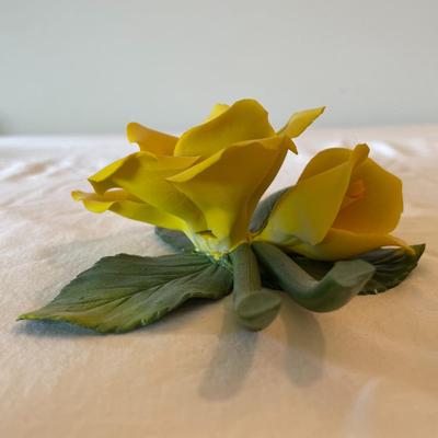 Sale Photo Thumbnail #129: Capodimonte porcelain figurine featuring a vibrant yellow rose, accompanied by green leaves and stems. The piece bears the original Capodimonte label and hallmark on the underside, indicating its authenticity. This handcrafted flower measures approximatel