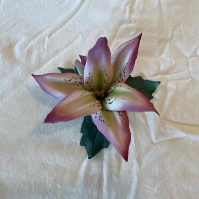 Sale Photo Thumbnail #163: Capodimonte porcelain lily flower figurine featuring detailed petals in soft pink and green hues. The underside is stamped with 'Capodimonte Made in Italy' and the distinctive crown and 'N' mark. In good condition with no visible chips or cracks.