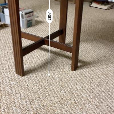 Sale Photo Thumbnail #345: Wooden side table featuring a 16-inch glass top surface and a height of 23 inches. The legs are constructed with cross-bar supports for added stability. The piece is finished in a dark brown stain and shows minor wear consistent with prior use. Practical 