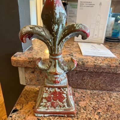 Sale Photo Thumbnail #62: Add a touch of French charm to your home or garden with this distressed fleur-de-lis finial. Heavy cast resin with worn red and sage green finish gives it a rustic, vintage look.

Details:

Approx. 10–12" tall

Beautiful ornate base

Great as a shelf ac