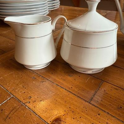 Sale Photo Thumbnail #109: Timeless and refined, this 1995 “Classic Elegance” fine china set by The Cellar includes dinner plates, salad plates, bowls, cups, a teapot, creamer, sugar bowl, and serving pieces. White with a thin gold rim, perfect for formal dining or holiday gath