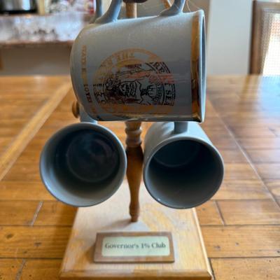 Sale Photo Thumbnail #207: Set of three vintage mugs with gold trim and the Great Seal of Idaho. Displayed on wood stand labeled “Governor’s 1% Club.