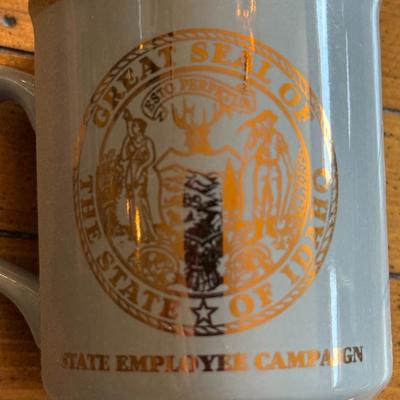 Sale Photo Thumbnail #209: Set of three vintage mugs with gold trim and the Great Seal of Idaho. Displayed on wood stand labeled “Governor’s 1% Club.