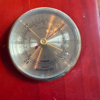 Sale Photo Thumbnail #255: Description: Wall-mounted weather station with three brass-tone dials — hygrometer, thermometer, and barometer — on a red-stained wood base. Vintage style.