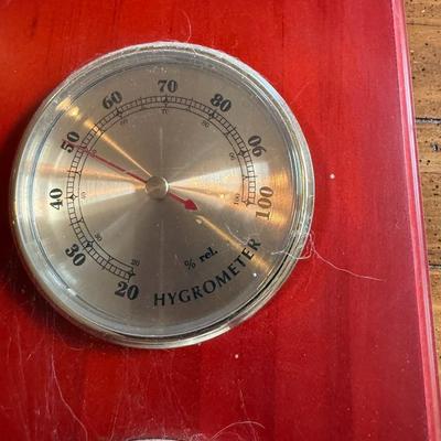 Sale Photo Thumbnail #257: Description: Wall-mounted weather station with three brass-tone dials — hygrometer, thermometer, and barometer — on a red-stained wood base. Vintage style.