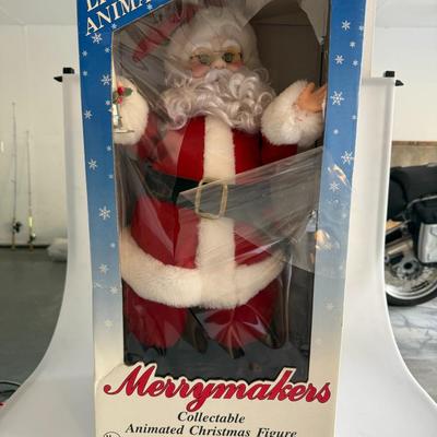 Sale Photo Thumbnail #434: Vintage lighted and animated Christmas Santa figure by Merrymakers. Holds a glowing candle and moves gently when plugged in. Original packaging with wear.