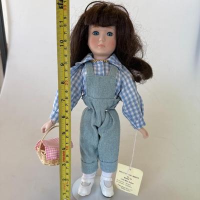 Sale Photo Thumbnail #180: Porcelain collector's doll representing July. Dressed in denim overalls and gingham blouse, holding a picnic basket. Comes with original tag.