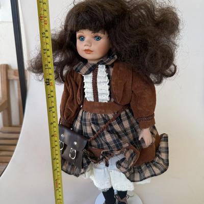 Sale Photo Thumbnail #182: Charming porcelain doll in a plaid school uniform with a brown velvet jacket and shoulder satchel. Detailed face and bright blue eyes.