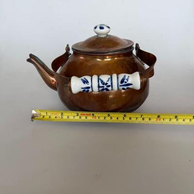 Sale Photo Thumbnail #223: Antique-style copper teapot with painted porcelain handle and knob. Features blue floral detail on ceramic and a warm patina on copper. Great for farmhouse decor or collectors.