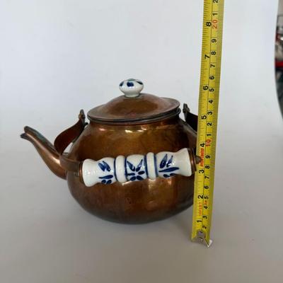 Sale Photo Thumbnail #222: Antique-style copper teapot with painted porcelain handle and knob. Features blue floral detail on ceramic and a warm patina on copper. Great for farmhouse decor or collectors.