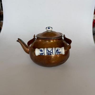 Sale Photo Thumbnail #221: Antique-style copper teapot with painted porcelain handle and knob. Features blue floral detail on ceramic and a warm patina on copper. Great for farmhouse decor or collectors.