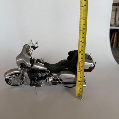 Sale Photo Thumbnail #226: Silver die-cast scale model of a Harley-Davidson touring motorcycle. Highly detailed with chrome accents, saddle bags, and functional kickstand. Display or gift item.