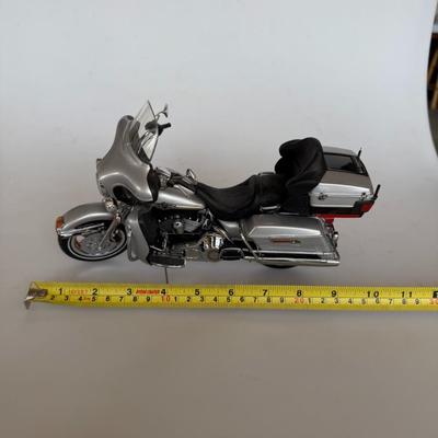 Sale Photo Thumbnail #227: Silver die-cast scale model of a Harley-Davidson touring motorcycle. Highly detailed with chrome accents, saddle bags, and functional kickstand. Display or gift item.