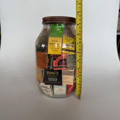 Sale Photo Thumbnail #245: Large glass jar filled with vintage matchbooks from various restaurants, hotels, and businesses — great for collectors or décor.