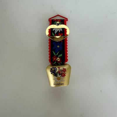 Sale Photo Thumbnail #311: Decorative brass bell with alpine floral design and "München" (Munich) label. Includes red-and-black fabric hanger.