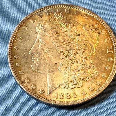 1884-O UNCIRCULATED TONED MORGAN SILVER DOLLAR AS PICTURED. (COIN #7166).