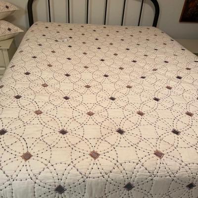 Queen mattress with black headboard and quilt comforter