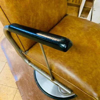LOT 86: Mid - Century Adjustable Barber’s Chair with Barber Capes and a Three Leg Roll About Stool