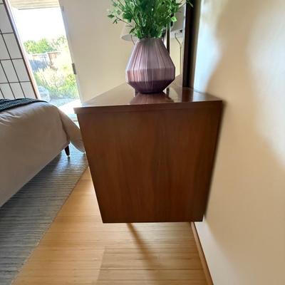 Sale Photo Thumbnail #3: The Stanley dresser is a mid-century modern piece designed for the bedroom. It features a medium wood tone with a walnut finish and chrome handles. Measuring 64 inches in length, 18 inches in width, and 30.5 inches in height, it offers nine drawers for am