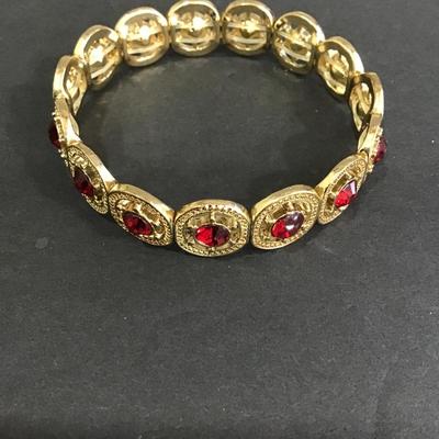 Gold tone, stretch bracelet with red rhinestones
