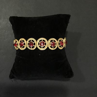 Gold tone, stretch bracelet with red rhinestones